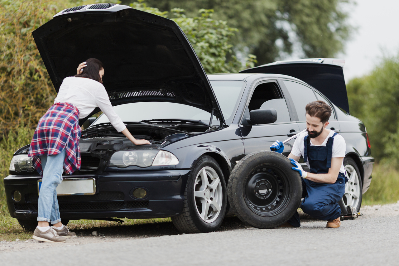 woman-checking-engine-man-changing-tyre_Easy-Resize.com