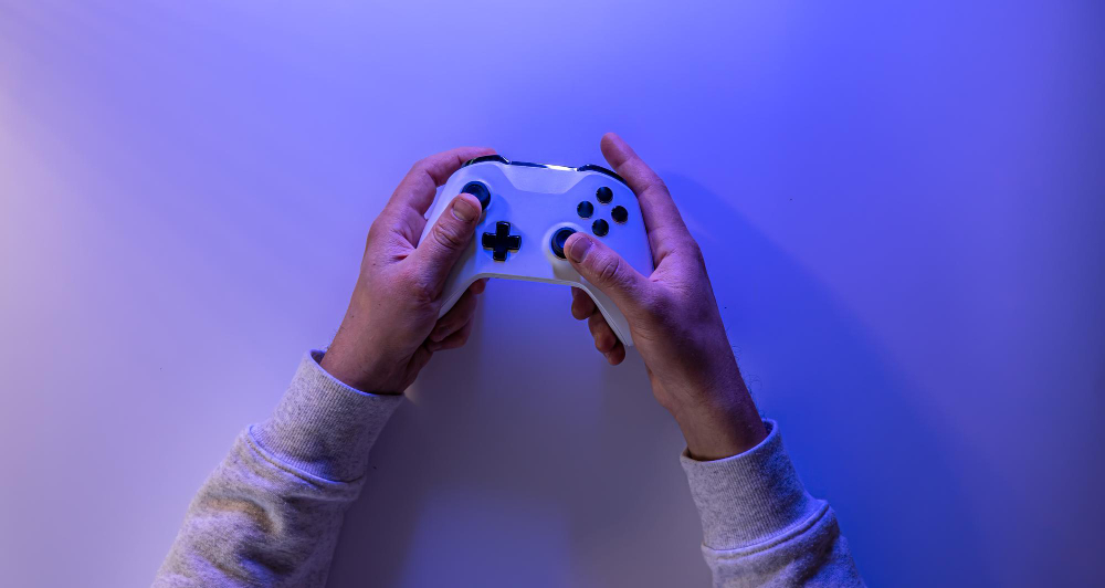 male-hands-hold-gamepad-blue-background-copy-space