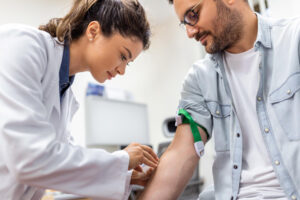 friendly-hospital-phlebotomist-collecting-blood-sample-from-patient-lab-preparation-blood-test-by-female-doctor-medical-uniform-table-white-bright-room